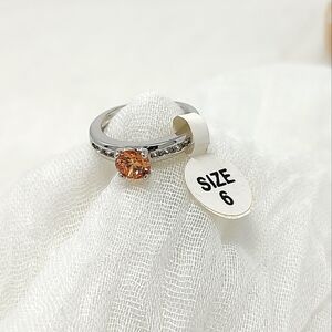 Size 6 silver and small crystal ring with orange color center stone